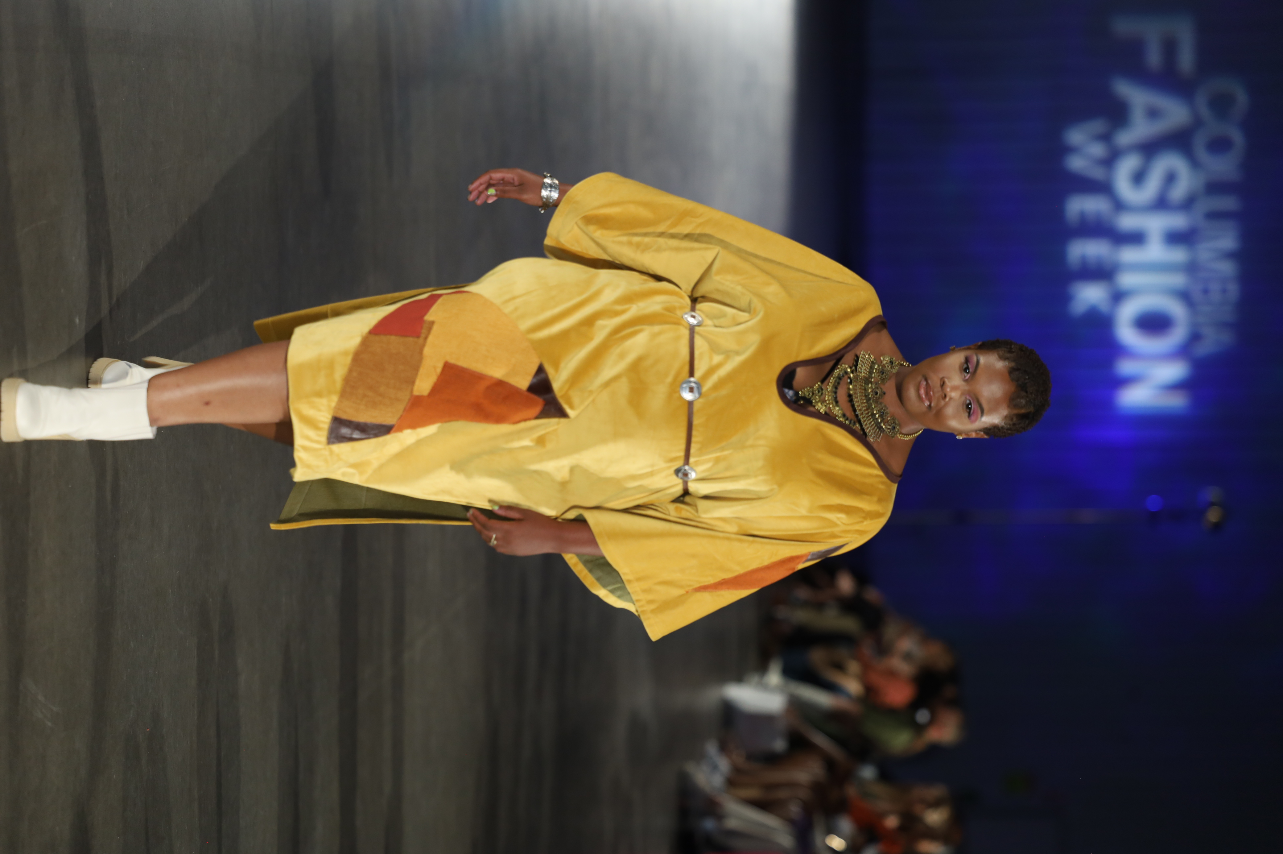 A flowing gold dress with colorful geometric panels on the runway, designed by Darrell Anderson