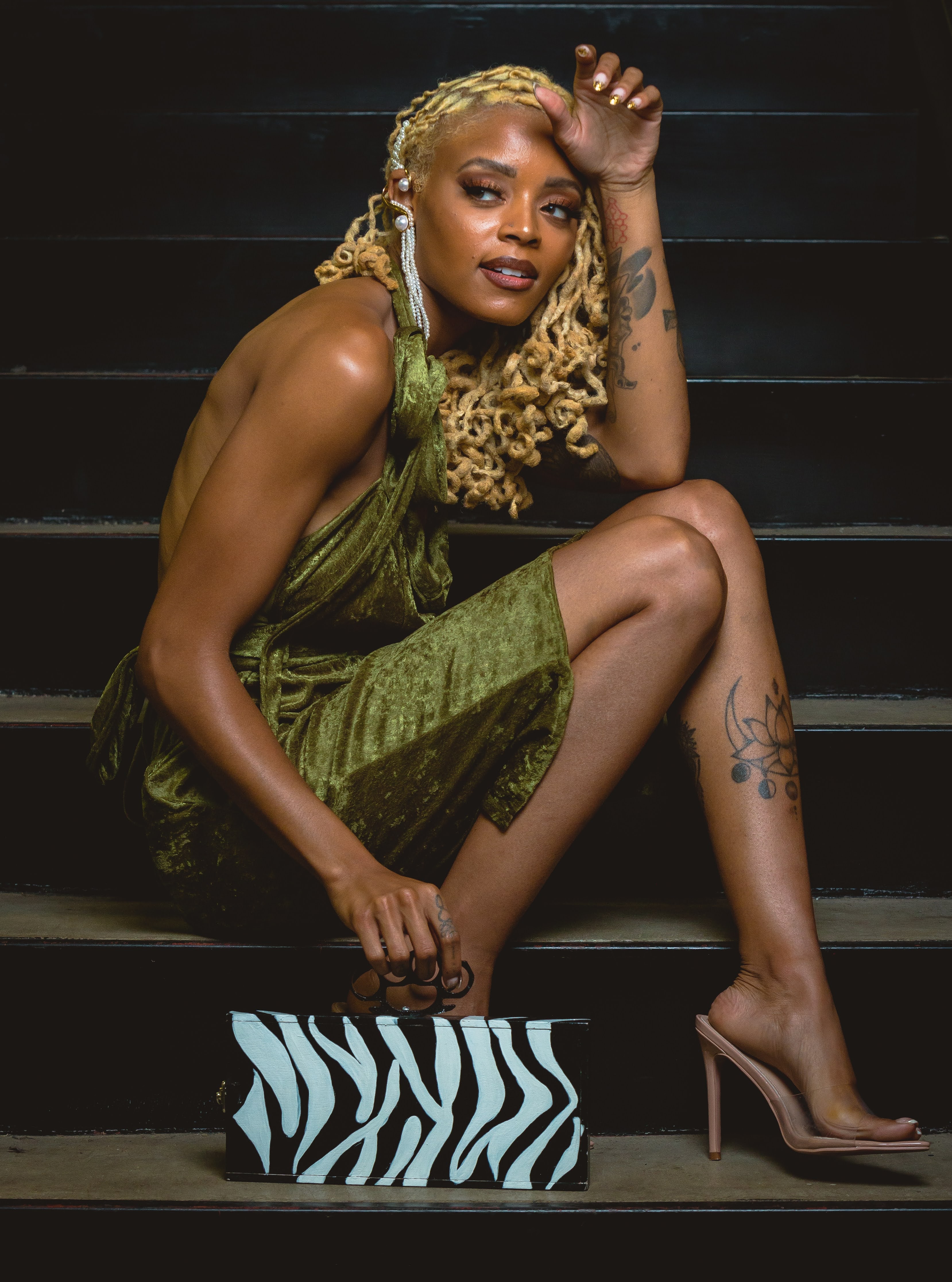 An olive-green velvet halter dress from St. Mark Vintage’s Eastern Opulence collection, photographed on a staircase